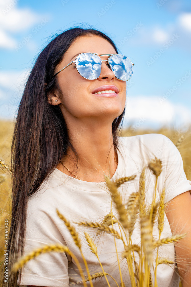 Portrait of a young woman in sunglasses with specular glasses in which white clouds are reflected