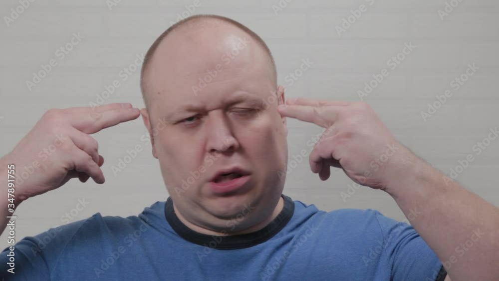 A bald man holds his fingers at his temples. Portrait of a bald man.