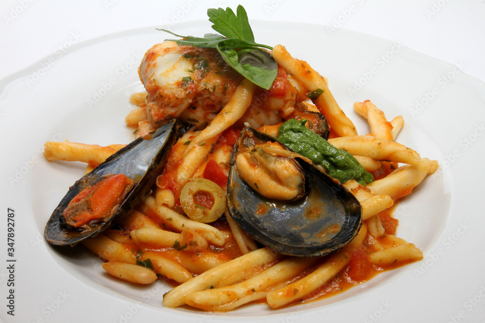 Pasta with mussels, fish, olives and tomato sauce. Italian cuisine
