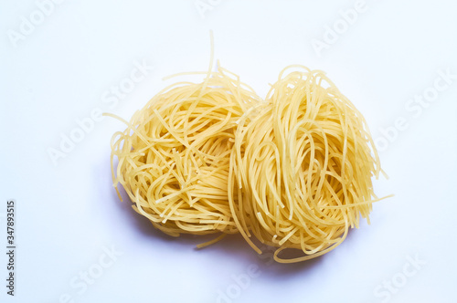 White background and thin Italian noodles, spaghetti, pasta of wheat, raw.