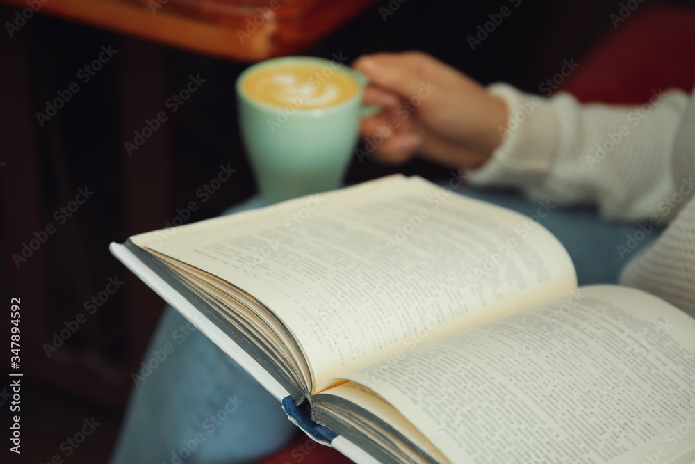 Woman with cup of coffee reading book indoors, closeup Woman with cup of coffee reading book indoors, closeup