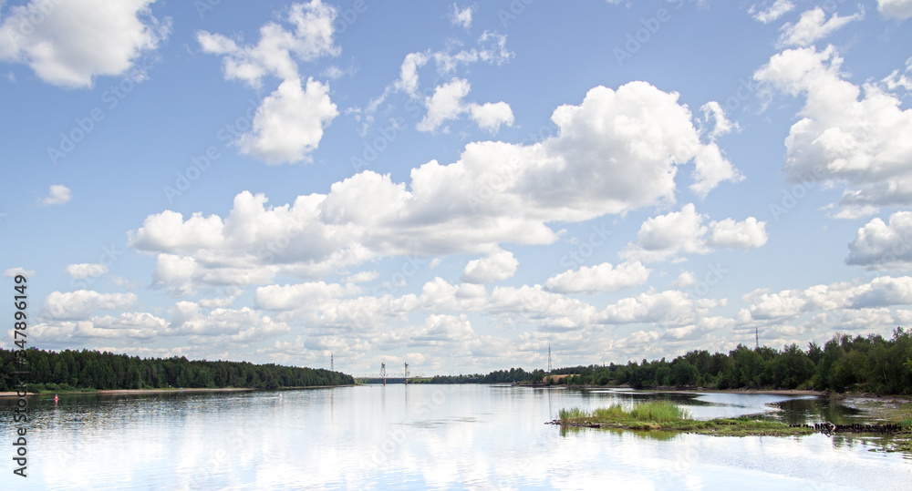 River coastline with forest. Cirrus clouds in the blue sky