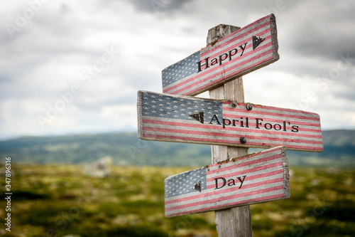 Happy april fools day text on wooden american flag signpost outdoors in nature.