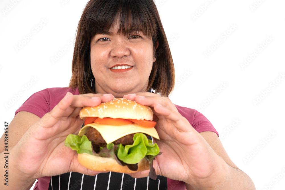 Overweight woman holding a hamburger and smiling, her very happy and enjoy to eat fast food. Concept of binge eating disorder (BED).
