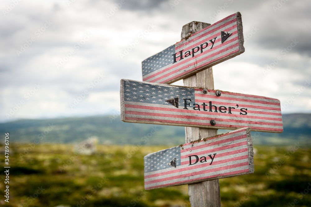 Happy fathers day text on wooden american flag signpost outdoors in nature.