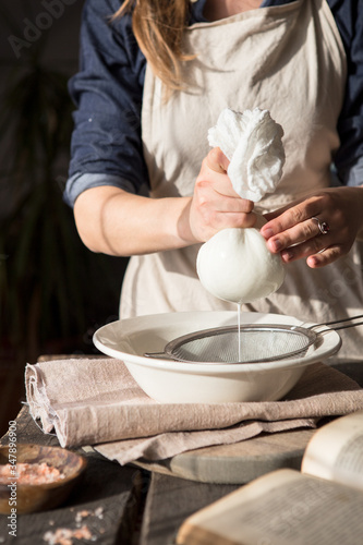 Preparation of cottage cheese - woman straining the milk through a cheesecloth