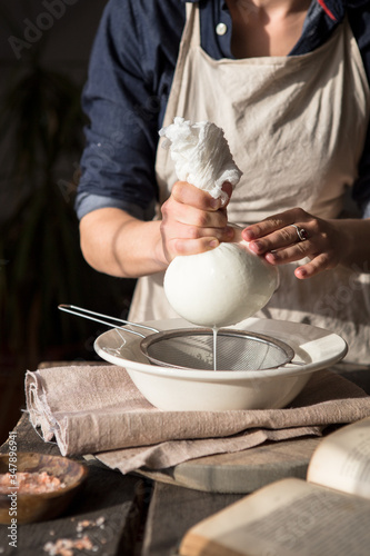 Preparation of cottage cheese - woman straining the milk through a cheesecloth