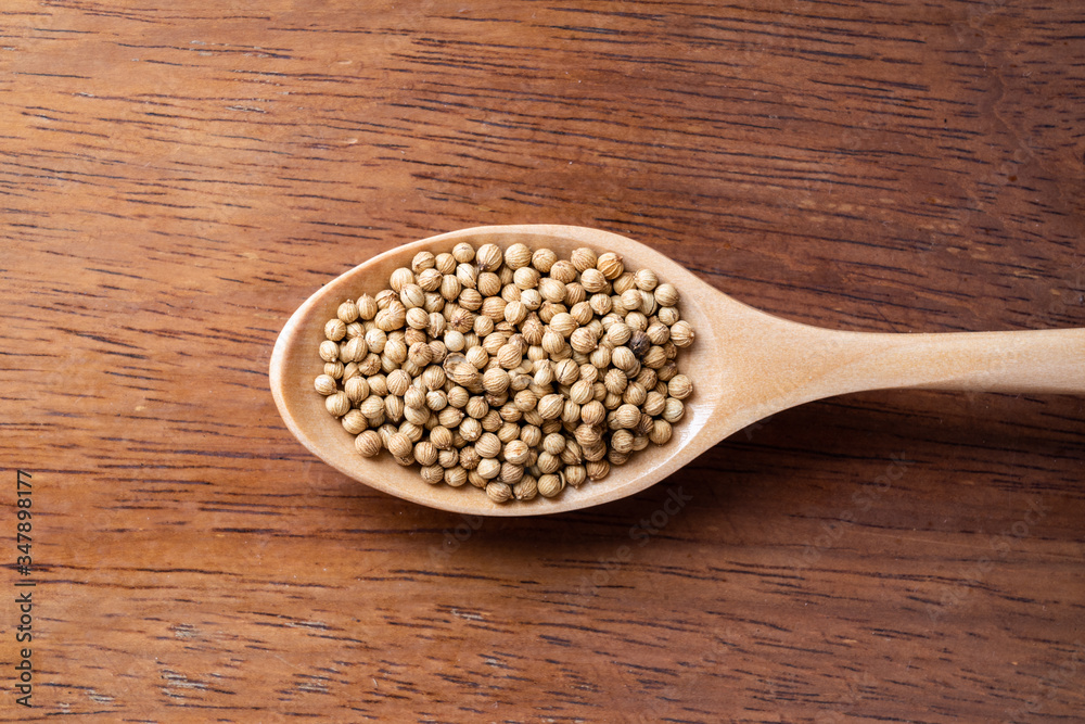 Coriander seed, spices, in wooden spoon on rustic wood table background Coriander seed, spices, in wooden spoon on rustic wood table background