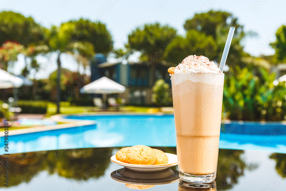 Φωτογραφία Glass of ice coffee and cookies on near swimming pool with blurred nature background