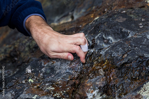 hand of a climber witha  strap on a rock 