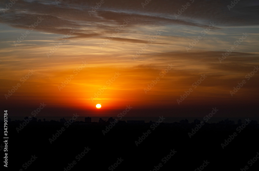 sunrise over the sea with city silhouette.