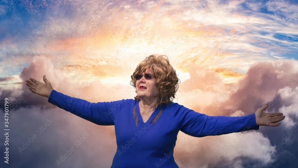 Cinemagraph Continuous Loop Animation. Elderly Woman with Hands Wide Open and Cloudy Colorful Sky in the Background. With Sunlight Cinemagraph Continuous Loop Animation. Elderly Woman with Hands Wide Open and Cloudy Colorful Sky in the Background. With Sunlight