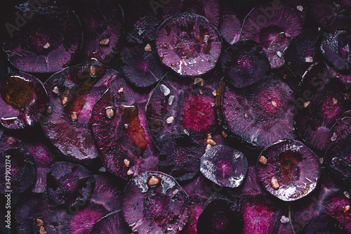 Slices of purple carrot with pink salt and olive oil for roasting. Macro photography, top view.