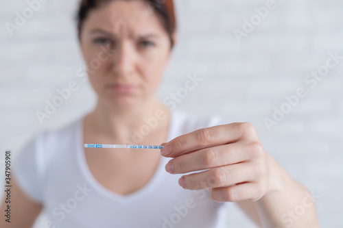 Sad woman shows a negative ovulation test. The concept of female infertility and low luteinizing hormone. Frustrated girl. photo