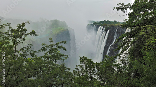 Miracle of nature Victoria Falls in Zambia. Powerful streams of water from the Zambezi River fall into the gorge from steep cliffs. Water fog is like smoke. An incredible sight.