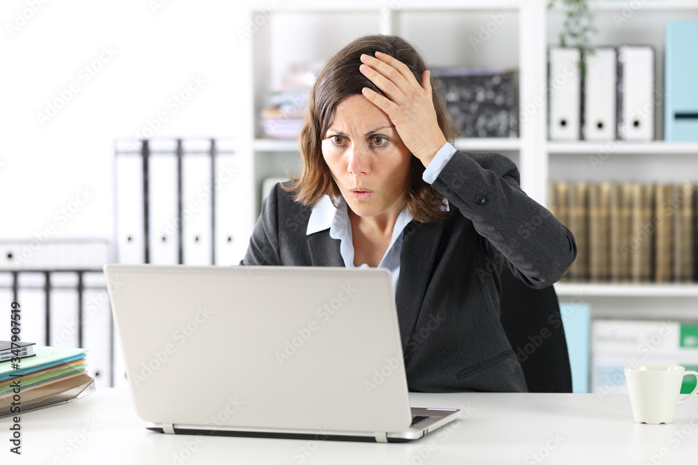 Surprised executive lady making mistake on laptop at office Surprised executive lady making mistake on laptop at office