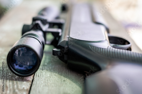 Sniper rifle lies on a wooden background. Optical sight close-up. The concept of hunting. photo
