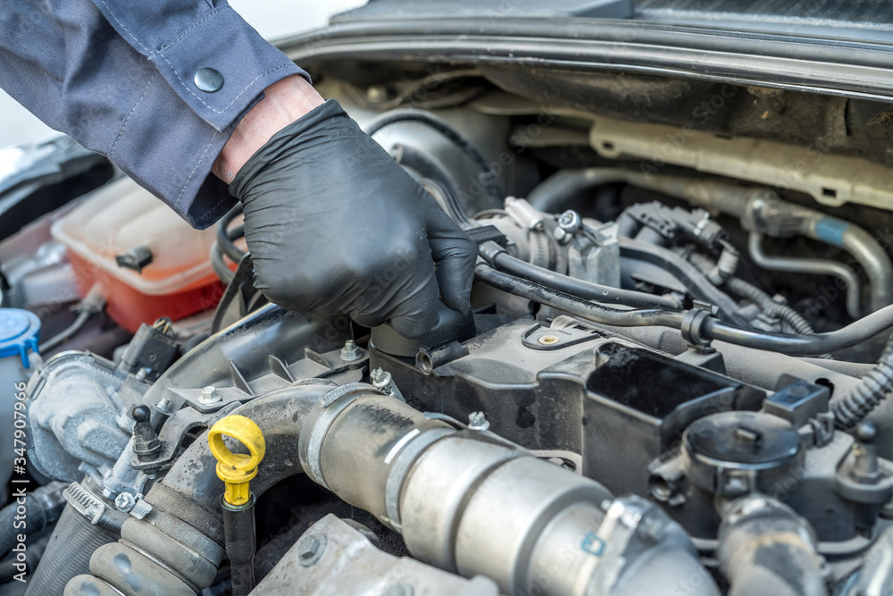 mechanic is opening the oil cap for change of oil from a car engine mechanic is opening the oil cap for change of oil from a car engine