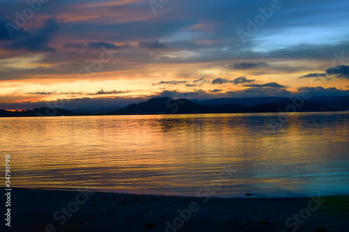 Bright colorful sunset over the sea, mountains on the horizon. Indonesia, view from Gili Asahan island to Lombok.