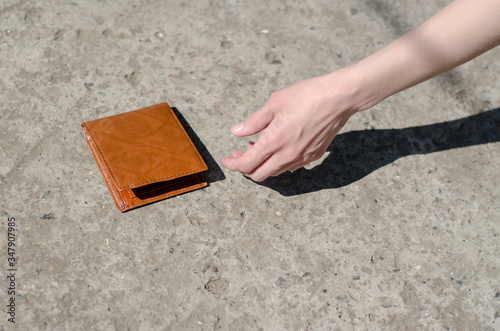Girl picks up a brown wallet. Found a wallet on the road.