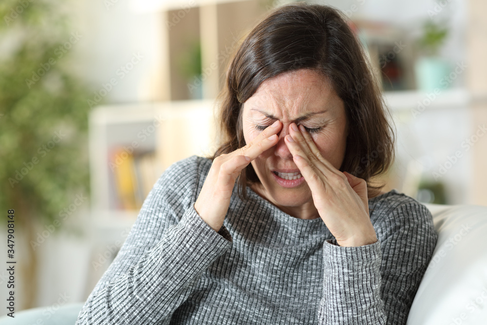 Middle age woman suffering eyestrain at home Middle age woman suffering eyestrain at home