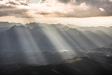 Golden light rays from clouds shining down to mountains. Sun rays over valley. Sun rays over hill. Beam of light from clouds on the mountains. Heaven in nature. Mon Pui Mok, Mae Moei, Tak, Thailand.