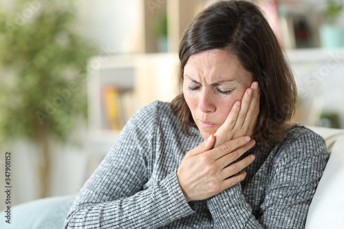 Middle age woman suffering toothache at home photo