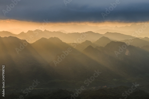 Golden light rays from clouds shining down to mountains. Sun rays over valley. Sun rays over hill. Beam of light from clouds on the mountains. Heaven in nature. Mon Pui Mok  Mae Moei  Tak  Thailand.