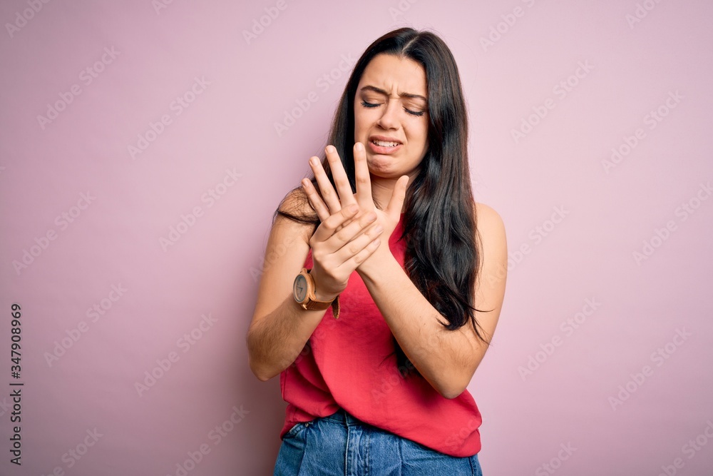 Young brunette woman wearing casual summer shirt over pink isolated background Suffering pain on hands and fingers, arthritis inflammation Young brunette woman wearing casual summer shirt over pink isolated background Suffering pain on hands and fingers, arthritis inflammation