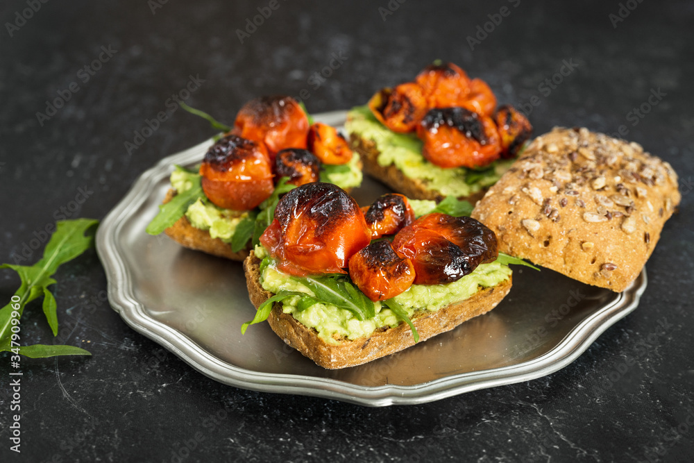 Close up of delicious vegan avocado sandwiched with arugula and roasted tomatoes Close up of delicious vegan avocado sandwiched with arugula and roasted tomatoes