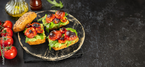Delicious vegan sandwiches with mashed avocado, roasted tomatoes and arugula