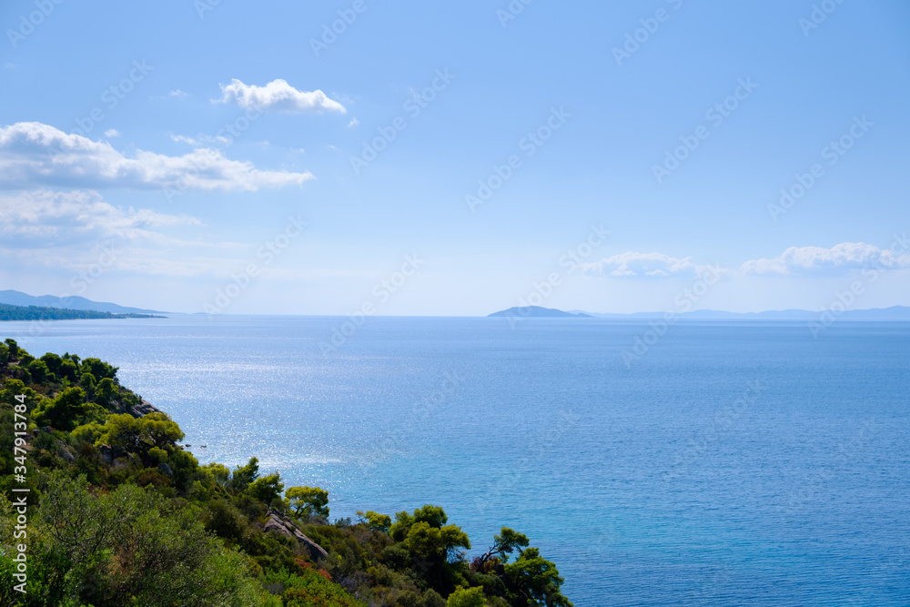 Amazing view from green hill to the  turquoise water and blue sky with island and white clouds in the background