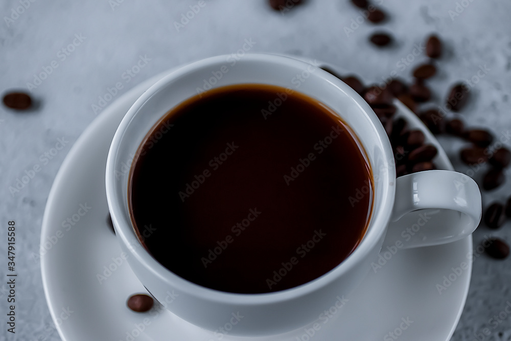 Obraz premium White cup with black coffee and coffee beans on a concrete. Soft focus.