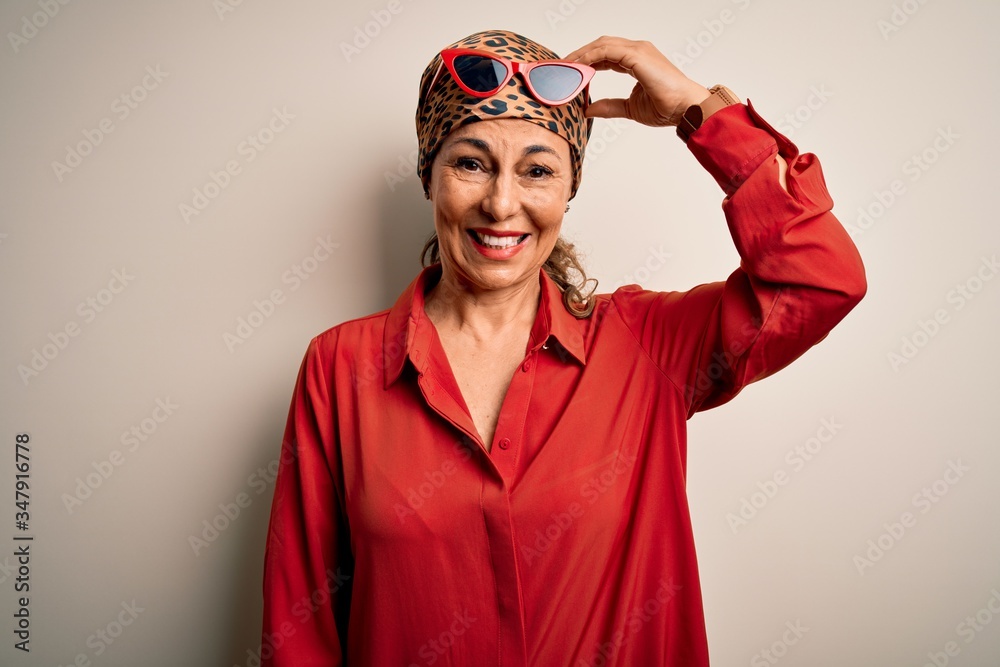 Middle age brunette woman wearing handkerchief on head and shirt over white background confuse and wonder about question. Uncertain with doubt, thinking with hand on head. Pensive concept. Middle age brunette woman wearing handkerchief on head and shirt over white background confuse and wonder about question. Uncertain with doubt, thinking with hand on head. Pensive concept.