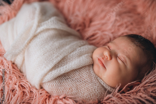 newborn baby in a cocoon sleeps cute on a pink tender bedspread