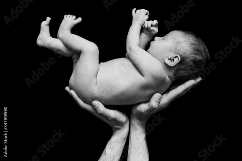 dad holds a newborn baby on a black background sleeps cute