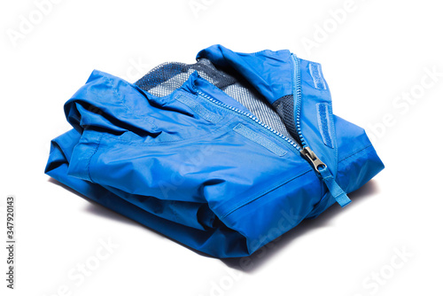 Folded blue zipper windbreaker jacket, rain proof and waterproof hiking Gore-Tex jacket hoodie. Track jacket sport nylon full zip isolated on white. Folded clothes. Outer layer garment for travel.