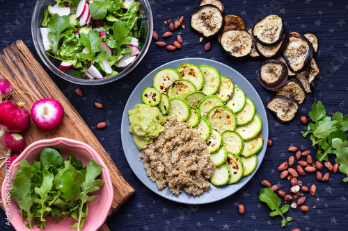 Baked roasted zucchini slices with cooked quinoa grain porridge on plate. Vegan balanced food.