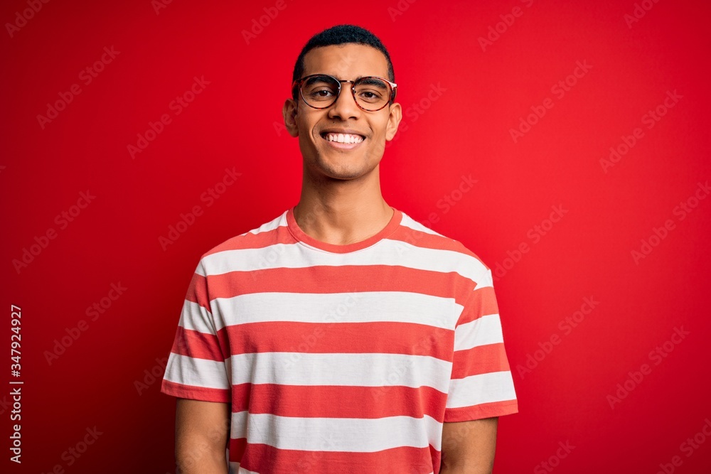 Young handsome african american man wearing casual striped t-shirt and glasses with a happy and cool smile on face. Lucky person. Young handsome african american man wearing casual striped t-shirt and glasses with a happy and cool smile on face. Lucky person.