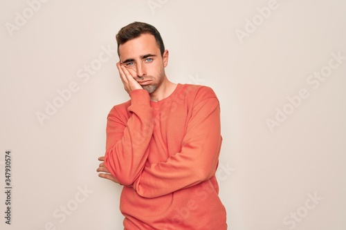Young handsome man with blue eyes wearing casual sweater standing over white background thinking looking tired and bored with depression problems with crossed arms.