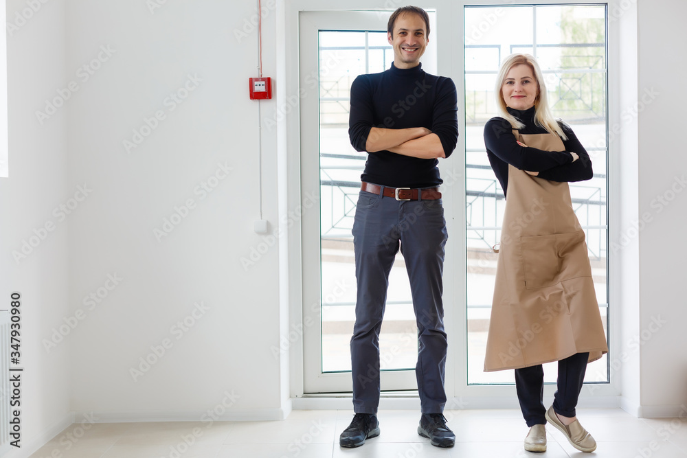 Fototapeta premium Coffee Business Concept - Barista couple in apron looking at camera ready to give Coffee Service at the modern coffee shop