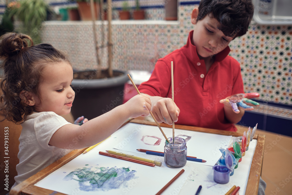 children playing in an inner courtyard and painting with water paints children playing in an inner courtyard and painting with water paints
