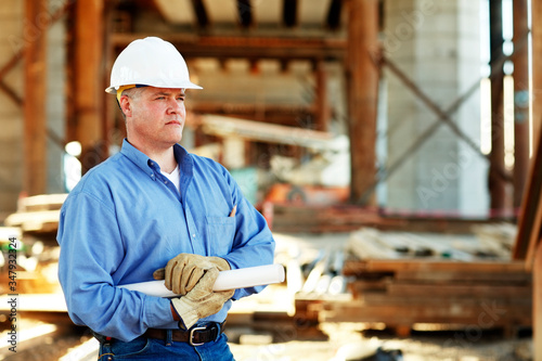Male construction foreman holding plans looking off camera