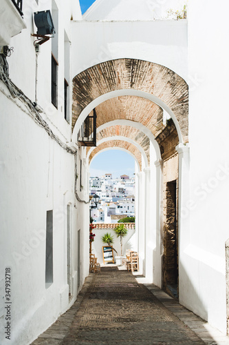 Old fashioned arch in white village with view of blue sky and buildins photo
