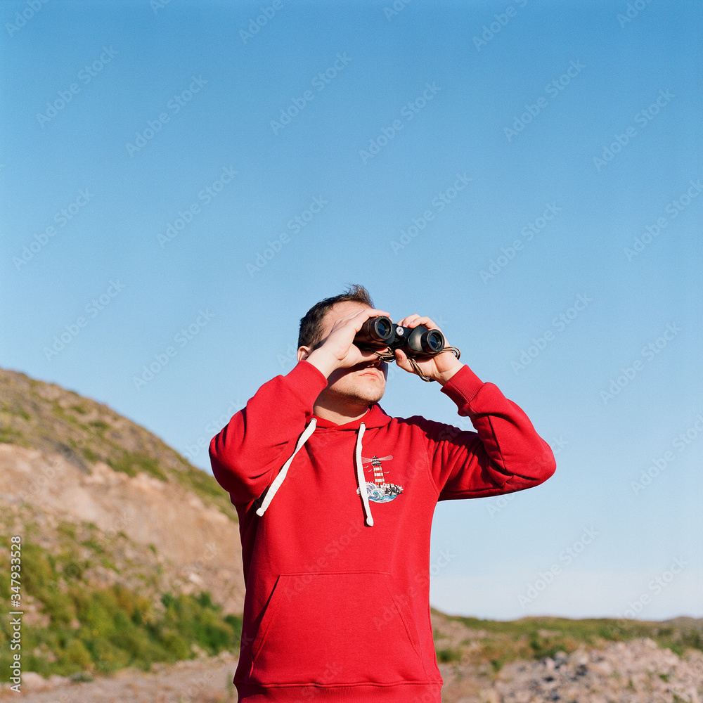 Man and woman stand at the foot of the mountain with binoculars Man and woman stand at the foot of the mountain with binoculars