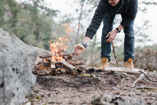 man putting sticks on a campfire outdoors in Sweden photo