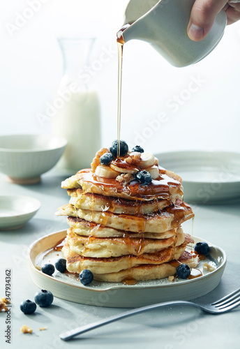 Stack of Blueberry Banana Walnut pancakes with Syrup Pouring Breakfast