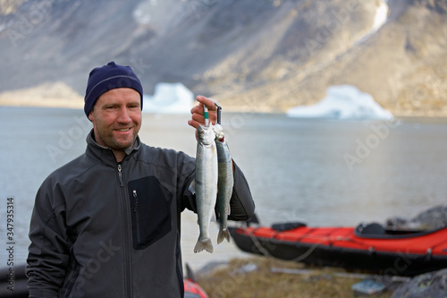 man holding up fresh Arctic Char in Greenland photo