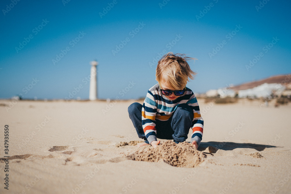 Boy child kid playing at the beach on a cold and windy day Boy child kid playing at the beach on a cold and windy day