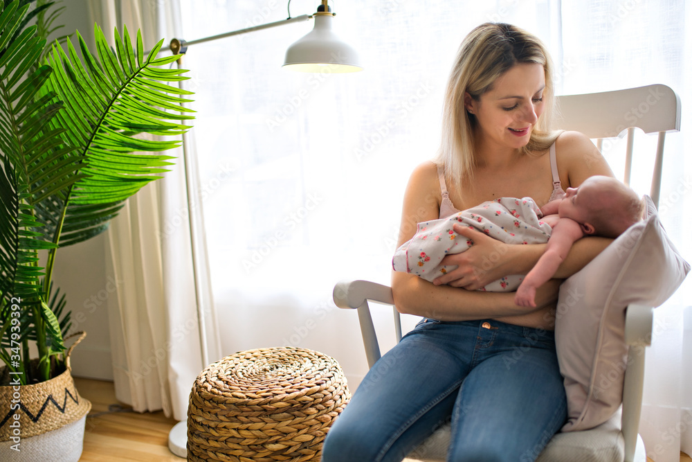 Φωτογραφία Young mother holding her newborn baby child sit on a chair in the living room